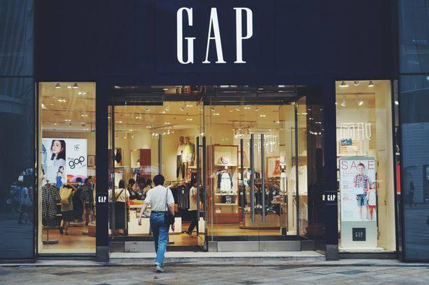 The illuminated entrance of a Gap retail store in the evening.