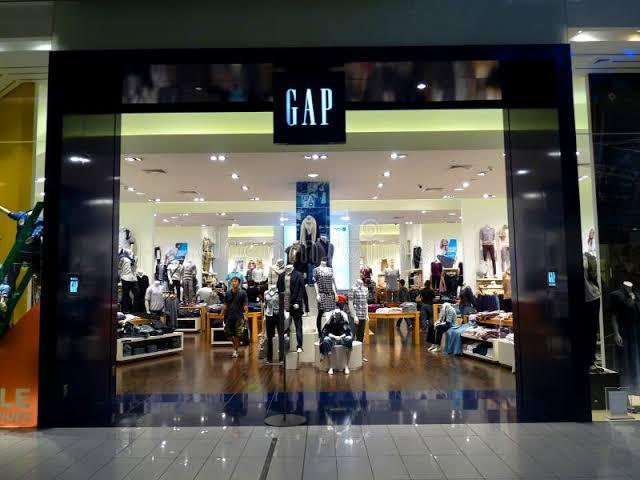 The illuminated entrance of a Gap retail store inside a shopping mall at night.